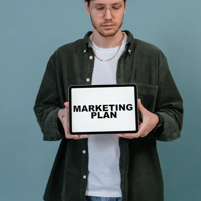 A person holding a tablet with a marketing plan on the screen